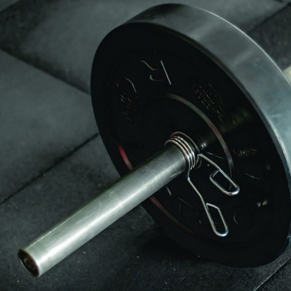 A barbell with a weight plate resting on a dark gym floor
