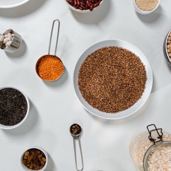 Bowls of grains, lentils and beans seen from above on a white table