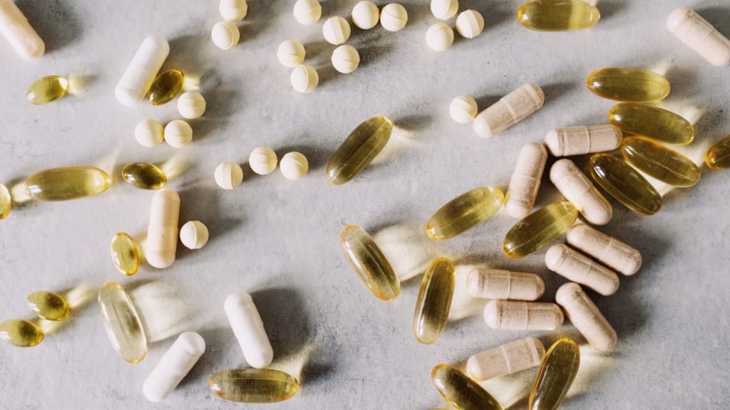 Capsules and tablets of different kinds spread across a marble surface