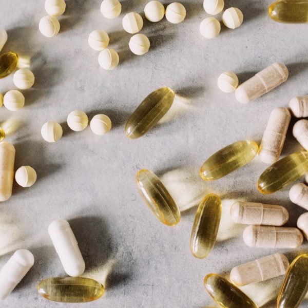 Capsules and tablets of different kinds spread across a marble surface
