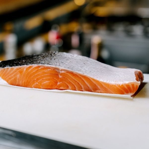 A fresh salmon fillet resting on a board in a kitchen